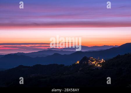 Aube se brisant sur la côte silhouetée du Cap Corse et l'ancien village de montagne de Speloncato en Corse Banque D'Images