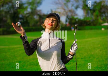 style de vie en plein air portrait de jeune belle et heureuse femme à jouer au golf tenant le ballon et le club de putter souriant gai dans le clothe de golf élégant Banque D'Images