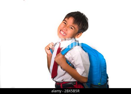 enfant doux de 7 ou 8 ans dans un sac de transport uniforme plein de livres se sentant contrarié et se plaignant du poids du sac à dos dans l'école paresseuse unha Banque D'Images