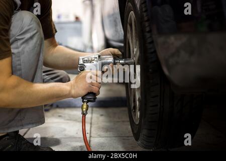 Professionnel service de voiture homme changeant la roue de voiture dans le centre de service de voiture Banque D'Images