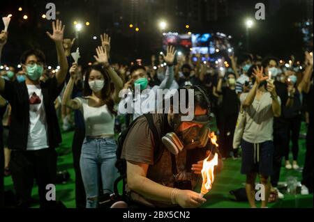 Un manifestant portant un masque tente d'éteindre le feu à la lueur des bougies lors de la commémoration de la veillée de la place Tienanmen au parc Victoria de Causeway Bay, à Hong Kong, le 04 juin 2020. Des milliers de personnes à travers Hong Kong se sont rassemblées et ont allumé des bougies le 4 juin pour commémorer le massacre de Tiananmen malgré l'interdiction du gouvernement contre les rassemblements. Banque D'Images