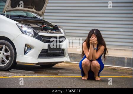 jeune femme désespérée et inquiète en stress, entordue sur le bord de la route avec une panne de moteur de voiture ayant un problème mécanique ayant besoin de réparation et d'assistance Banque D'Images