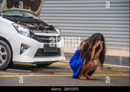 jeune femme désespérée et inquiète en stress, entordue sur le bord de la route avec une panne de moteur de voiture ayant un problème mécanique ayant besoin de réparation et d'assistance Banque D'Images