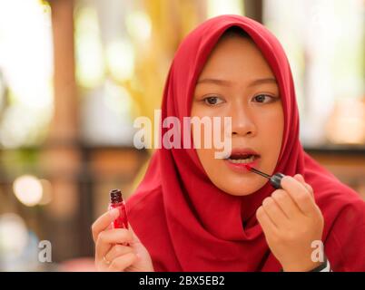 Miroir reflet de la jeune femme musulmane heureuse et belle dans hijab traditionnel foulard appliquer le maquillage et les cosmétiques joyeuse dollarisation dans beau Banque D'Images