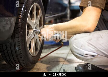 Professionnel service de voiture homme changeant la roue de voiture dans le centre de service de voiture Banque D'Images