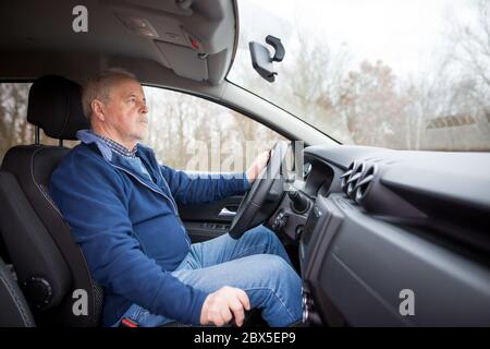 Un vieil homme senior conduisant une voiture moderne, concept de transport Banque D'Images