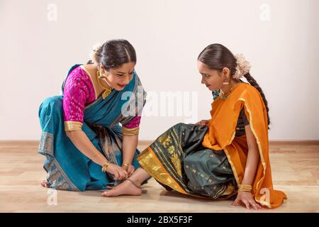 La danseuse de Bharatnatyam attachant un anklet sur les pieds de son élève. Banque D'Images