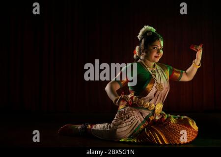 Bharatnatyam danseuse jouant veena pendant sa performance devant un fond sombre. Banque D'Images