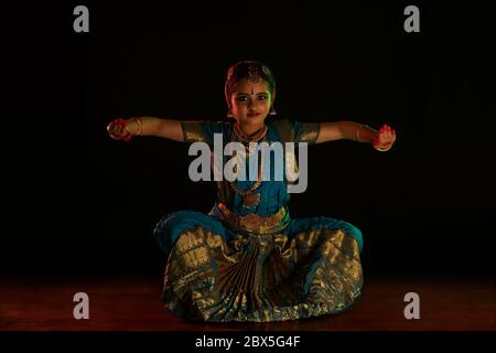 Jeune danseuse de bharatnatyam assise dans la mudra de natyarabham pendant sa représentation. Banque D'Images