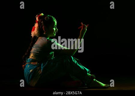 Jeune danseur de bharatnatyam assis sur scène pendant un spectacle. Banque D'Images