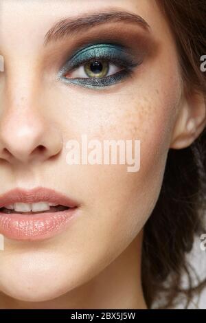 Gros plan sur la partie femelle du maquillage du visage. Femme avec le maquillage naturel de beauté de visage de vogue de soirée. Fille avec une peau parfaite et des yeux bleus sha Banque D'Images