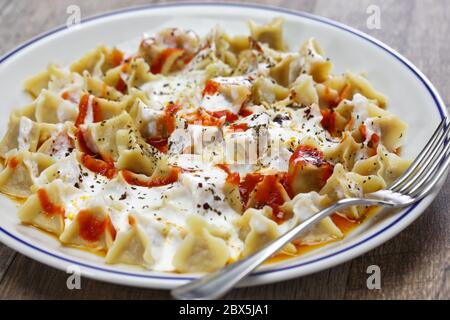 le manti (boulettes de ravioli turques) servi avec du yaourt à l'ail, du beurre de poivre d'alep fondu et de la menthe et du sumac secs Banque D'Images