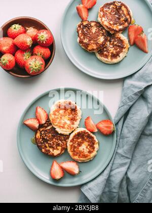 Crêpes au fromage sur l'assiette fraises servies. Crêpes au fromage cottage, syrniki, beignets à la ricotta, beignets au caillé. Vue de dessus ou plan d'étapage. Verticale. Banque D'Images
