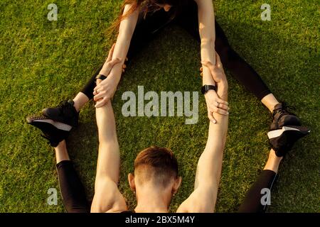 Homme et femme athlétiques faisant un exercice différent sur une pelouse verte Banque D'Images