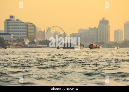 Très fréquentée rivière Chao Phraya avec des bateaux passagers et des gratte-ciels au coucher du soleil à Bangkok, Thaïlande Banque D'Images