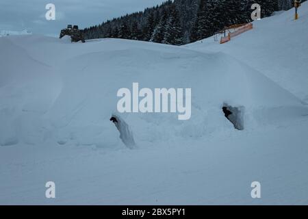 Ancienne ferme de cabane de montagne enneigée dans la région de ski de Saalbach Hinterglemm dans les alpes autrichiennes avec deux trous menant à deux entrées Banque D'Images