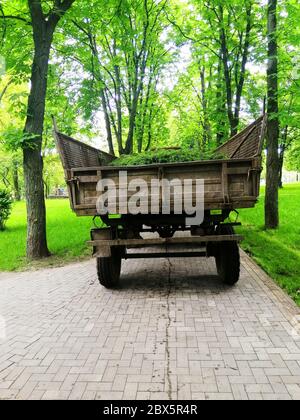 Remorque de tracteur avec herbe verte fauchée dans un parc public. Vie urbaine. Transport communautaire. Nettoyage de la zone. Technologies. Image d'arrière-plan. Environnement Banque D'Images