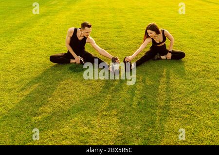 Homme et femme athlétiques faisant un exercice différent sur une pelouse verte Banque D'Images