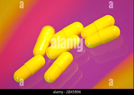 7 Lansoprazole jaune 15mg capsules comprimés contre fond violet pâle magenta Banque D'Images