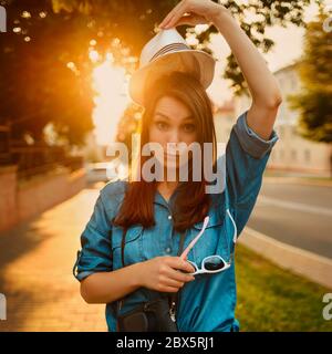 portrait d'une femme élégante en chapeau sous le soleil du matin avec un appareil photo Banque D'Images