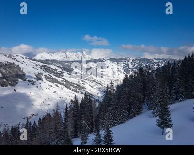 Vue panoramique sur les montagnes enneigées de la région skiable de Saalbach Hinterglemm dans les alpes autrichiennes, contre un ciel bleu Banque D'Images