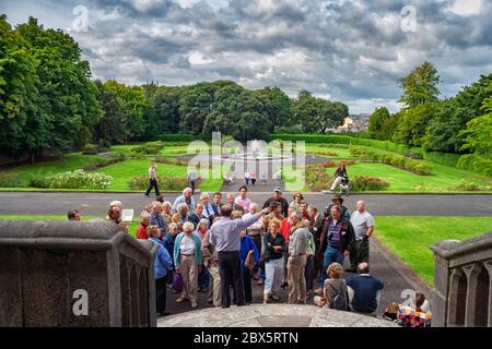 Groupe de touristes lors de la visite, les gens écoutent le guide de visite aux jardins du château de Kilkenny à Kilkenny, Irlande Banque D'Images