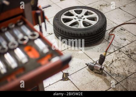 Pistolet à vide pour le remplacement des roues de la voiture sur le sol, concept de transport, centre de service de voiture Banque D'Images