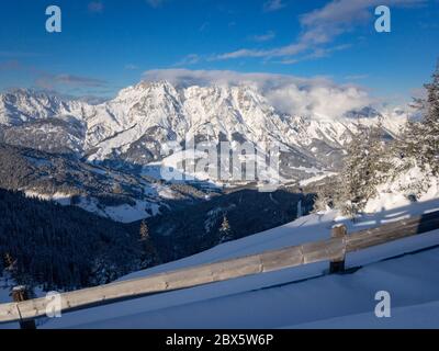 Vue panoramique sur les montagnes enneigées de Leogang enveloppées dans des nuages dans les alpes Austrain contre le ciel bleu Banque D'Images