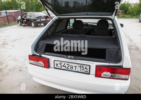 Novosibirsk, Russie - 05/20/2020: Un hayon russe blanc moderne avec un hayon ouvert sur le fond d'un modèle de voiture LADA 2114 en noir, an Banque D'Images