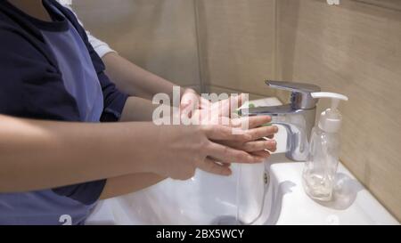 Mère et garçon se lavant les mains ensemble. Maman aide son fils à se laver les suds de savon de ses mains sous l'eau courante. Concept de planification familiale Banque D'Images