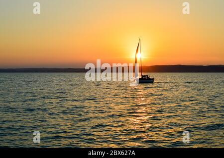 Coucher de soleil pittoresque sur le lac Balaton, Hongrie avec voilier avant le soleil. Banque D'Images