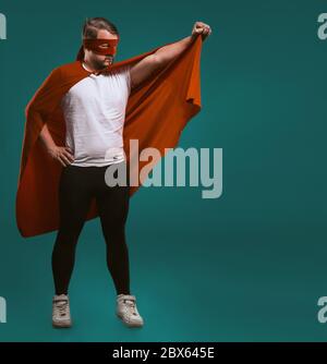 Super héros sauveur homme prêt à voler. Le brave homme légendaire en masque rouge tient son manteau prêt à sauver le monde du crime. Isolé sur vert de gascogne Banque D'Images