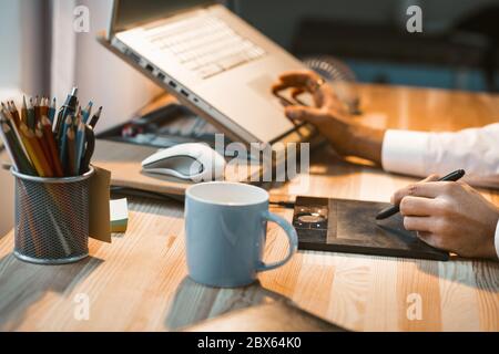 Un freelance travaille tard dans la nuit. Jeune designer travaille des heures supplémentaires de dessin nouveau projet sur tablette graphique et ordinateur. Gros plan du concepteur Banque D'Images