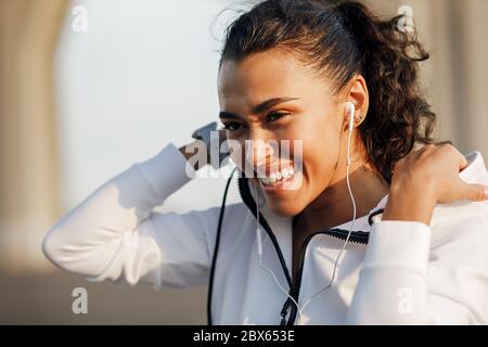 Portrait d'une jeune femme portant un sweat à capuche et souriant après un entraînement Banque D'Images