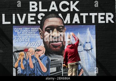 NOTEZ LE CONTENU GRAPHIQUE DE L'artiste MURAL Micky Doc enlève une photo utilisée pour peindre une murale à George Floyd au mur international de Belfast sur la route des chutes. M. Floyd a été tué le 25 mai alors qu'il était en garde à vue dans la ville américaine de Minneapolis. La fresque a été commandée par Feile an Phobail et Failte Feirste Thiar, et peinte par Marty Lyons et Micky Doherty. Banque D'Images