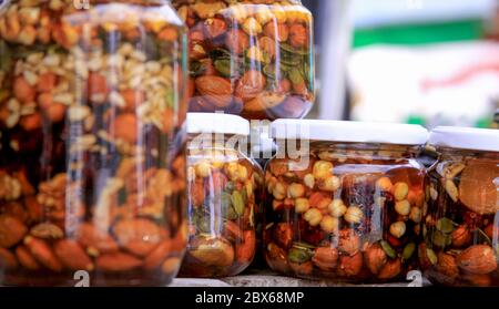 Divers types de noix dans des pots de miel. Le miel est une substance alimentaire douce et visqueuse faite par les abeilles et certains insectes apparentés. Banque D'Images