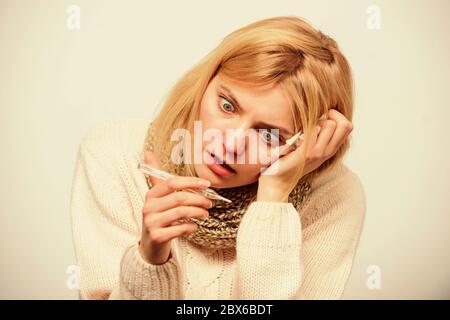 Mesurer la température. La fièvre de la pause des recours. La prise de température et d'évaluer les symptômes. Concept à haute température. Femme se sent gravement malade l'éternuement. Fille en tissu écharpe tenir thermomètre et close up. Banque D'Images