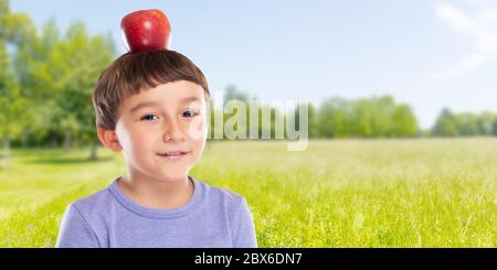 Petit enfant garçon avec des fruits rouges de pomme sur sa tête en plein air copyspace copier l'espace sain manger concept à l'extérieur Banque D'Images