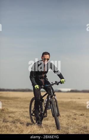 Jeune homme qui fait du vélo sur un terrain d'herbe Banque D'Images