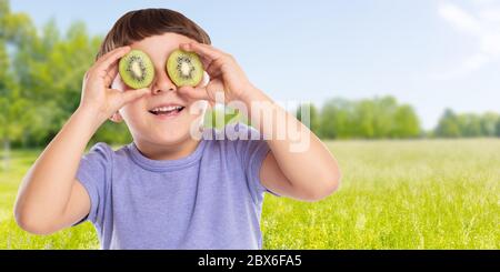 Jeune enfant petit garçon kiwi fruit ayant amusant bannière copyspace copie espace extérieur heureux bonheur sain manger à l'extérieur Banque D'Images