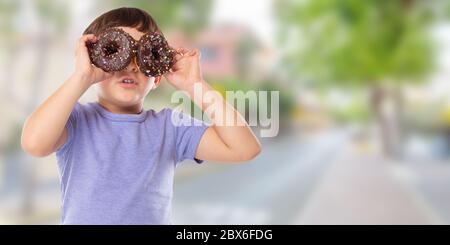 Garçon enfant avec beignes beignes ayant plaisir heureux bonheur bannière copyspace ville malsaine manger à l'extérieur Banque D'Images