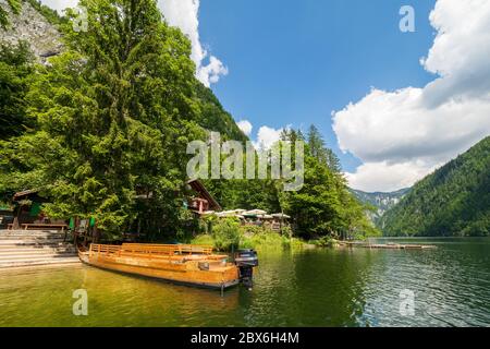 Vue sur un 'Plätte', un bateau plat traditionnel, amarré au bord de la mer à côté d'un restaurant de poissons au lac Toplitz, région de l'Ausseer Land, Styrie, Autriche Banque D'Images