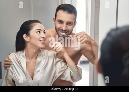 Jeune couple aimant attrayant pratiquant l'hygiène dentaire ensemble Banque D'Images
