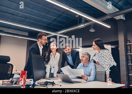 De jeunes collègues discutent de nouveau contrat avec un patron à cheveux gris au bureau Banque D'Images