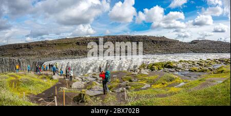 Vue panoramique sur la plus grande et la plus puissante cascade d'Europe appelée Dettifoss en Islande, près du lac Myvatn, avec un ciel spectaculaire et des touristes Banque D'Images