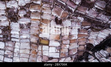 Vue aérienne des étangs d'évaporation de sel dans une mine de sel à Maras, Pérou. Différentes formes et couleurs d'étangs créent des motifs et des formes abstraits. Banque D'Images