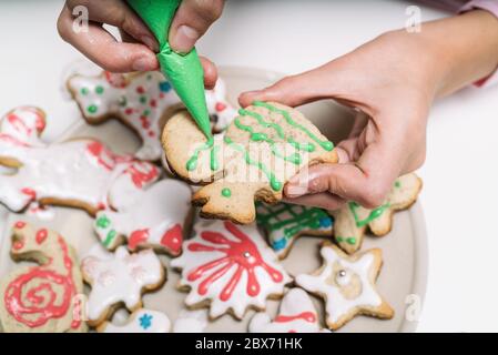 Les mains de petite fille faisant des biscuits de Noël traditionnels. L'enfant décorera les biscuits de Noël faits maison sur une table blanche Banque D'Images