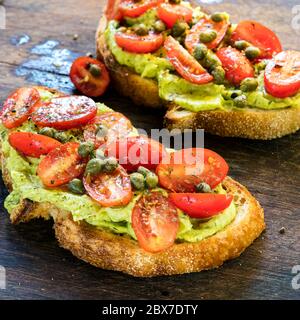 Toast à l'avocat avec tomates cerises et salsa au câpres. Pain au levain. Banque D'Images