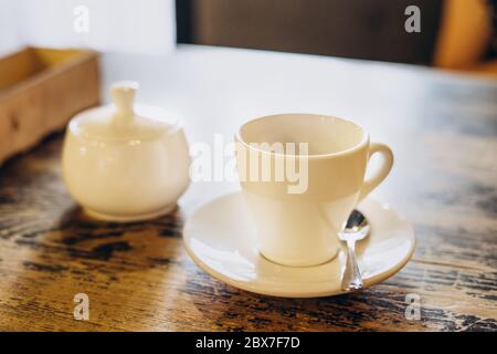 Café frais aromatique dans une tasse blanche. Americano avec un bol à sucre sur la table dans le café. Americano dans une petite tasse blanche Banque D'Images