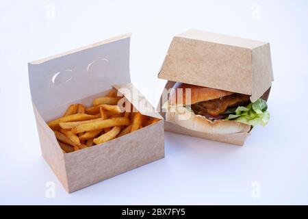 De délicieuses frites croquantes et un grand hamburger juteux. Dans des boîtes ouvertes en carton durable. Sur fond blanc. Banque D'Images